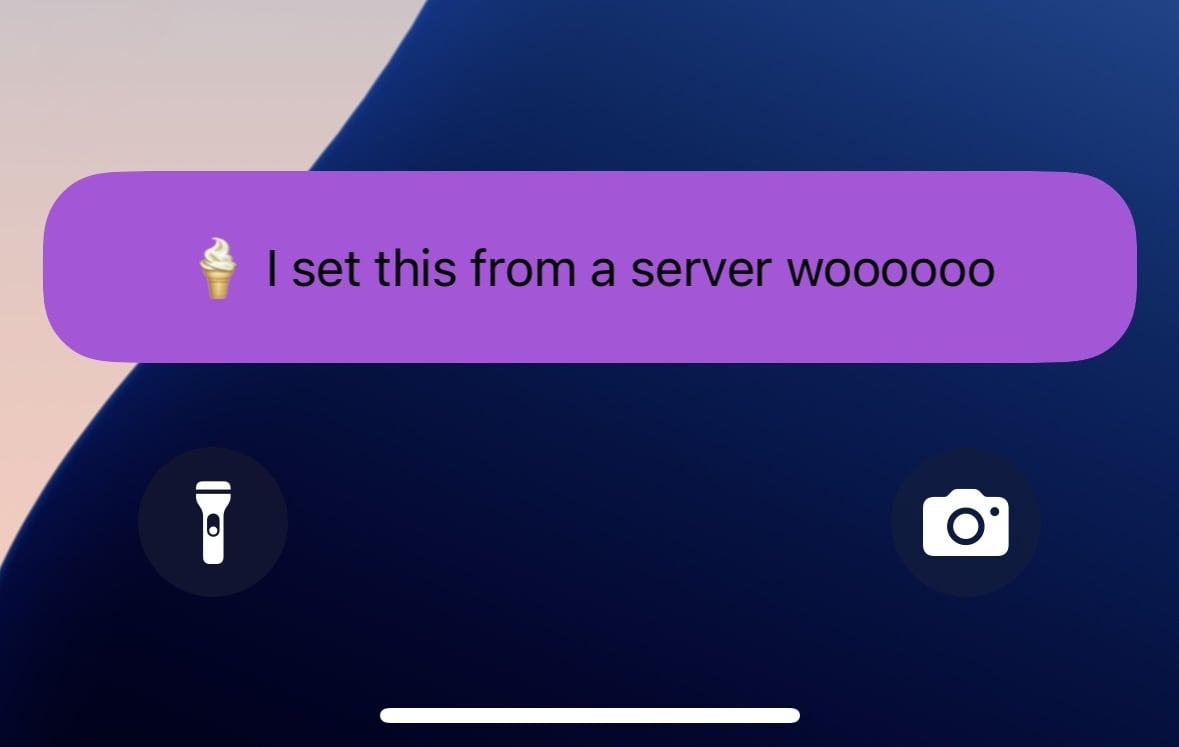 A Live Activity on an iOS Lock Screen with an emoji and the text 'I sent this from a server woooooo'.