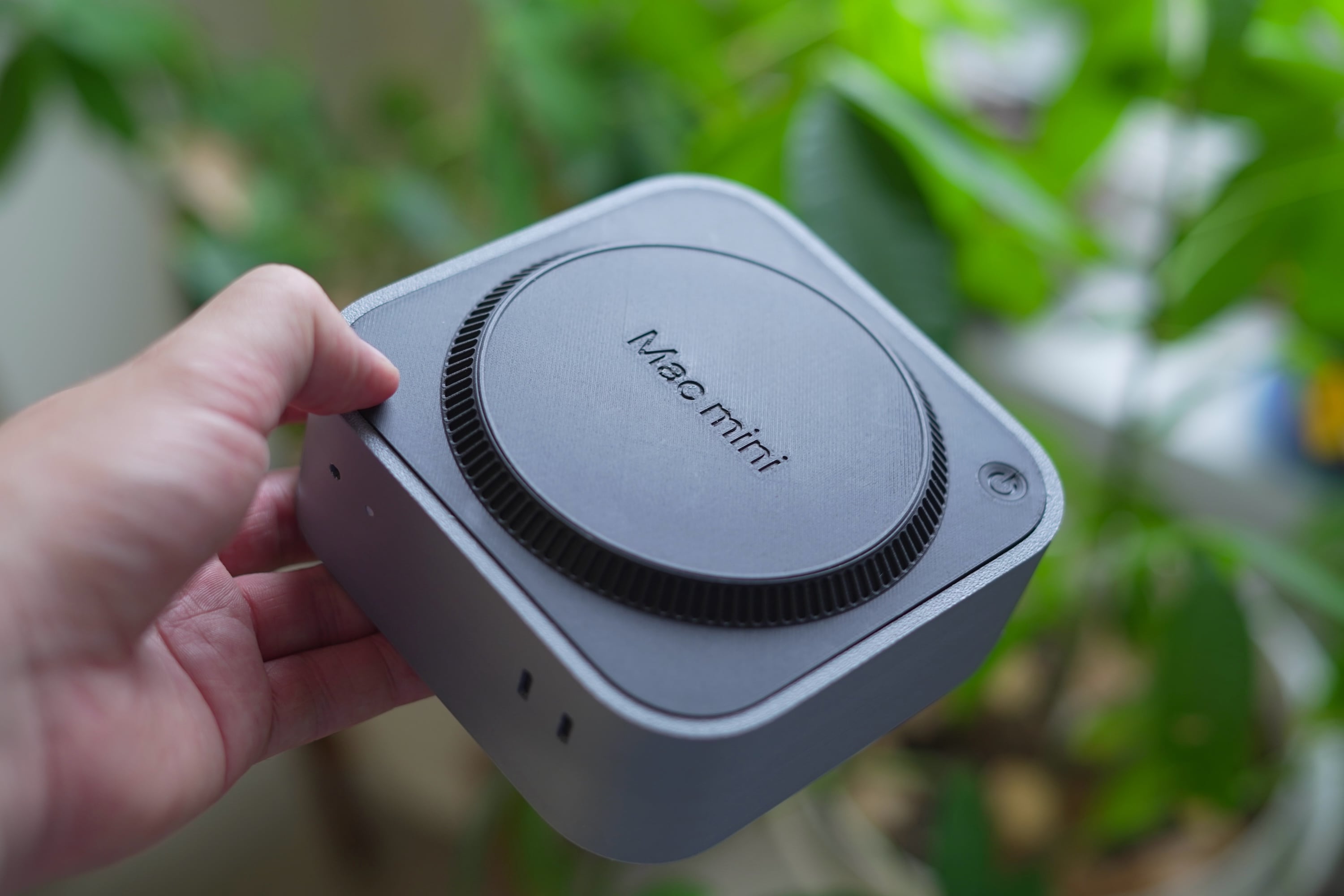 My hand holding the 3D printed Mac mini showing its back