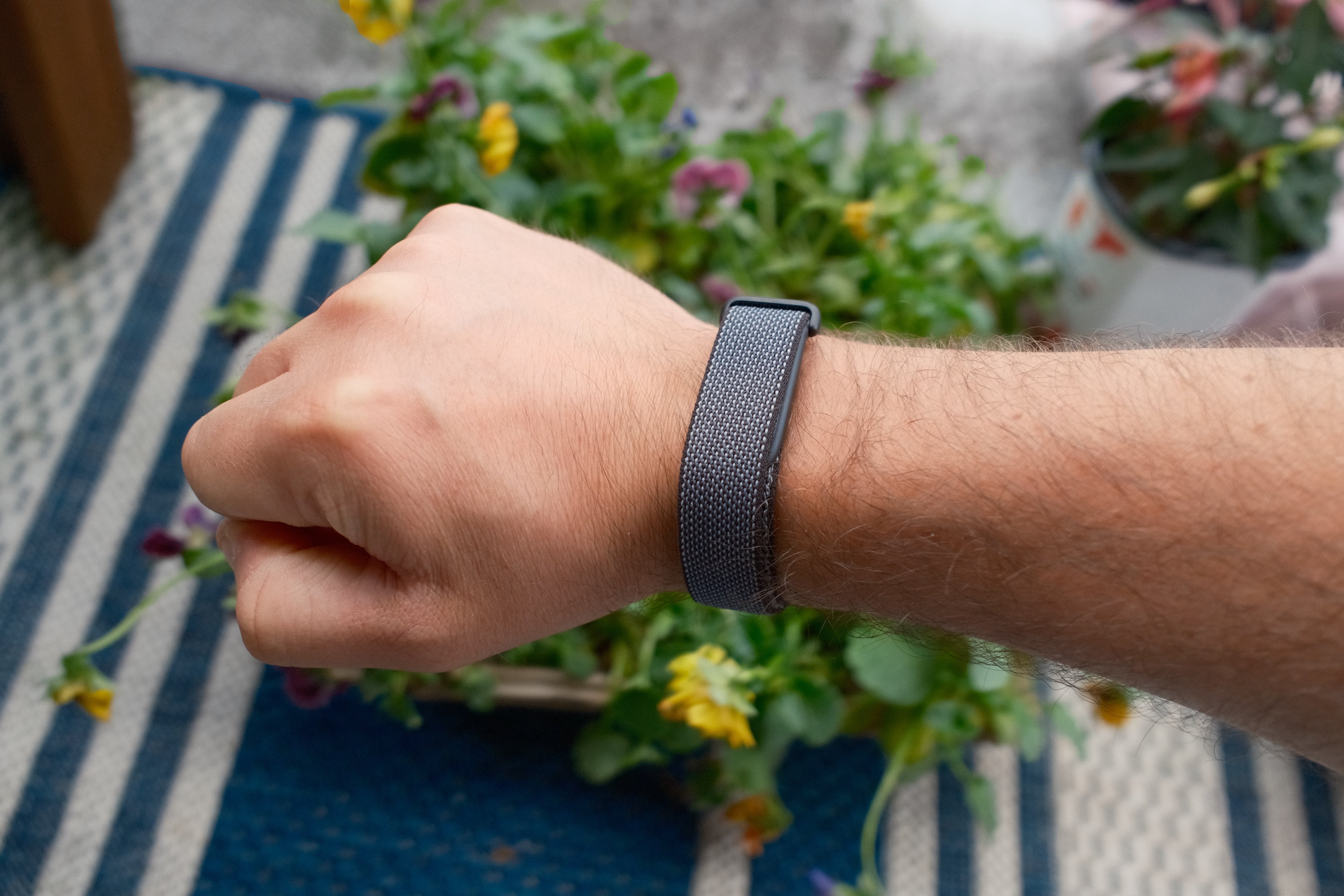 Obsidian Fitbit Air on wrist in front of some flowers